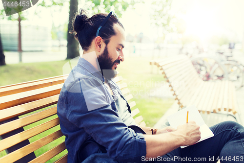 Image of man with notebook or diary writing on city street