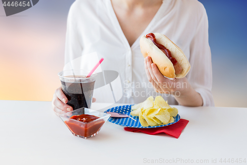 Image of close up of woman eating hot dog with cola