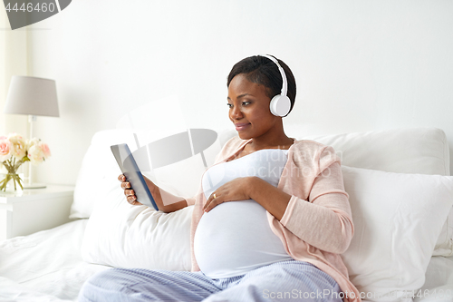 Image of pregnant woman in headphones with tablet pc