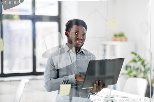 Image of businessman with laptop at office glass board