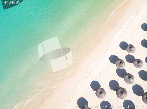 Image of Aerial view of amazing tropical white sandy beach with palm leaves umbrellas and turquoise sea.