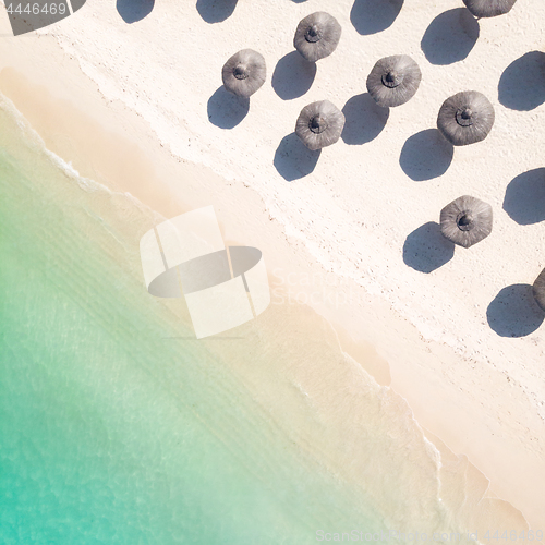 Image of Aerial view of amazing tropical white sandy beach with palm leaves umbrellas and turquoise sea.