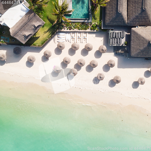 Image of Aerial view of amazing tropical white sandy beach with palm leaves umbrellas and turquoise sea, Mauritius.