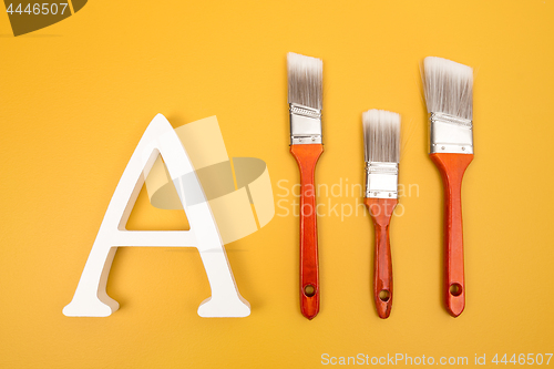 Image of Letter A and paintbrushes on yellow background