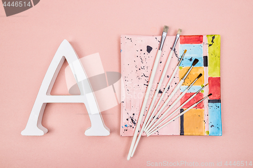 Image of Letter A and paintbrushes on a colorful plate