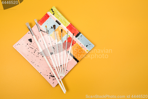 Image of White paintbrushes on a colorful ceramic plate