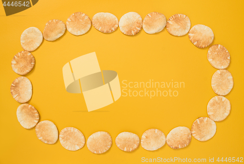 Image of Frame made of mini pita bread on yellow background