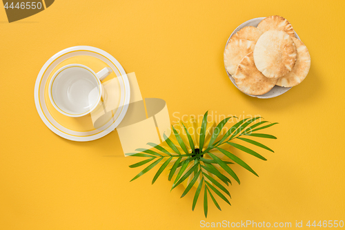 Image of Teacup, palm leaves and and plate with pita bread