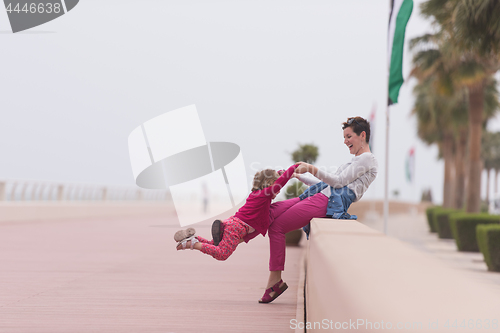 Image of mother and cute little girl on the promenade by the sea