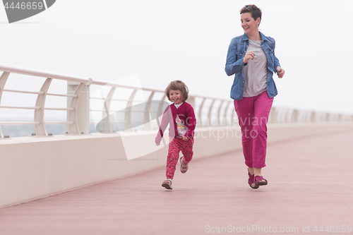 Image of mother and cute little girl on the promenade by the sea