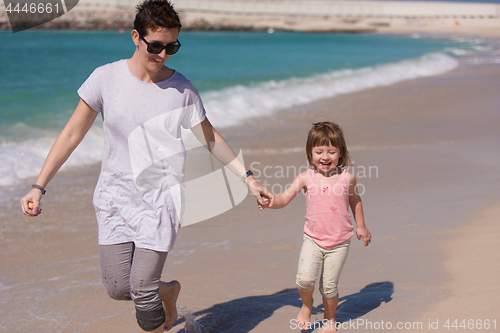 Image of mother and daughter running on the beach