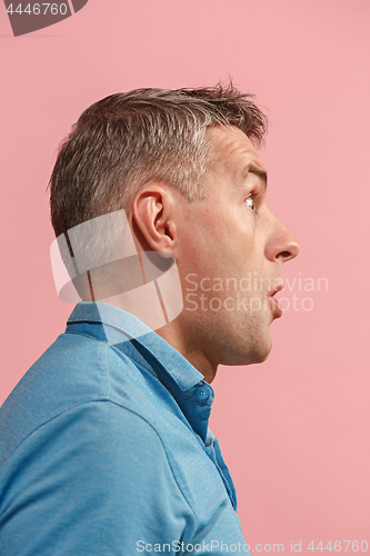 Image of The young attractive man looking suprised isolated on pink