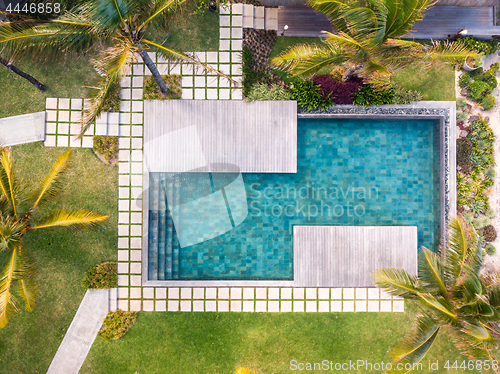 Image of Aerial view of luxury hotel resort with swimming pool with stair and wooden deck surrounded by palm trees.