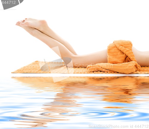 Image of long legs of relaxed lady with orange towel