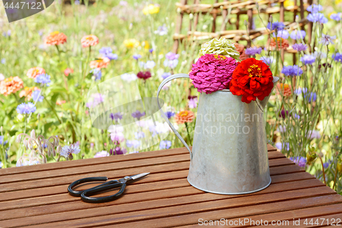 Image of Scissors next to a rustic jug holding freshly cut zinnias