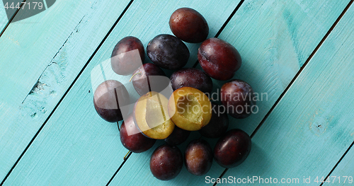 Image of Pile of ripe plums on blue wood