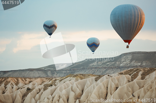 Image of Three hot air balloons flying over the rocks of Cappadocia