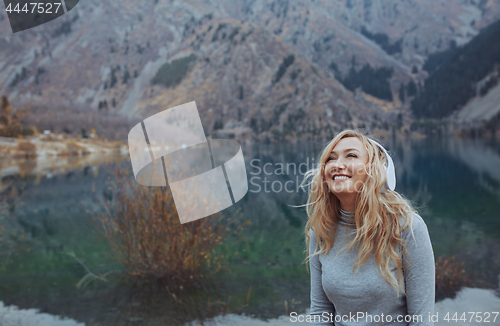 Image of Woman wearing wireless headphones at the mountain lake