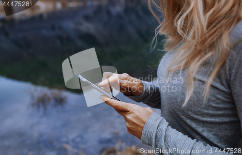 Image of Woman using smartphone at the lake