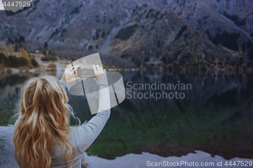 Image of Woman making mobile photo at the mountain lake