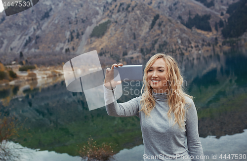 Image of Smiling woman makes selfie at the mountain lake