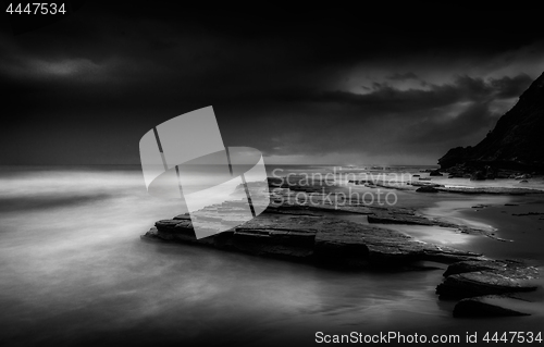 Image of Dark storm clouds moving out to sea at dawn