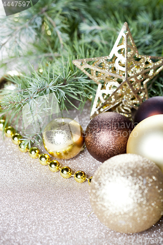 Image of Christmas fir tree branch, golden star, brown balls.