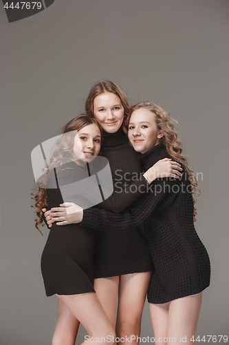 Image of The fashion girls standing together and looking at camera over gray studio background