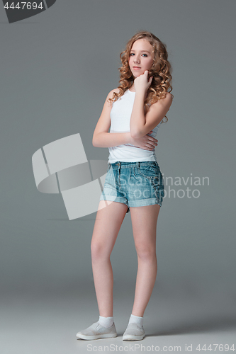 Image of Full length of young slim female girl in denim shorts on gray background