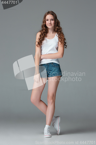 Image of Full length of young slim female girl in denim shorts on gray background