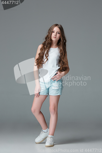 Image of Full length of young slim female girl in denim shorts on gray background