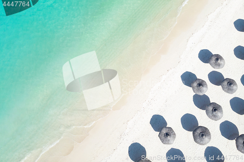 Image of Aerial view of amazing tropical white sandy beach with palm leaves umbrellas and turquoise sea.