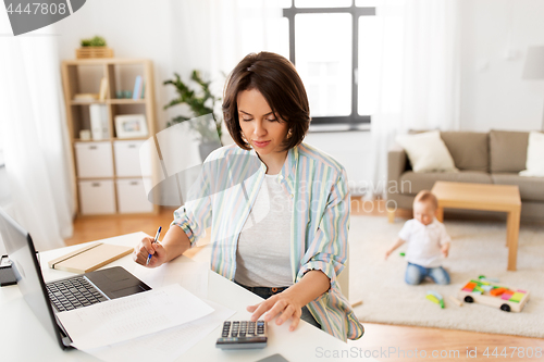 Image of working mother counting on calculator and baby