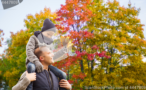 Image of happy father carrying son with autumn maple leaves