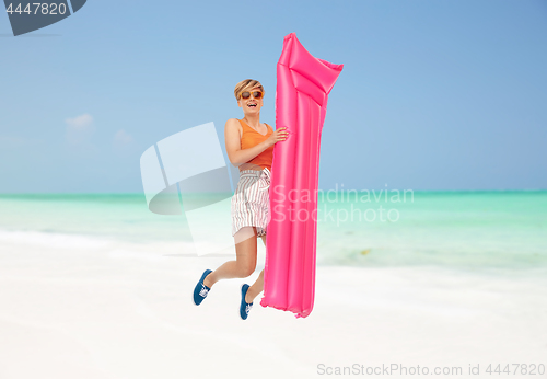 Image of teenage girl jumping with float mattress on beach