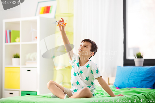 Image of happy little boy playing with airplane toy at home