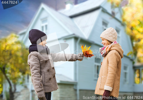 Image of kids with autumn maple leaves over house outdoors