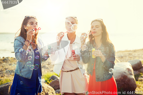 Image of young women or girls blowing bubbles on beach