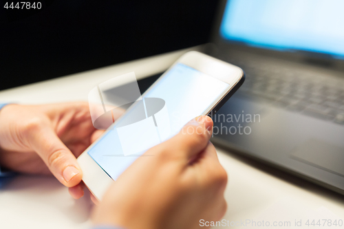 Image of close up of hands with smartphone at night office