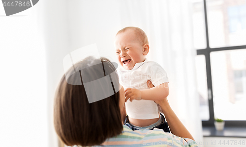 Image of mother holding crying little baby son at home