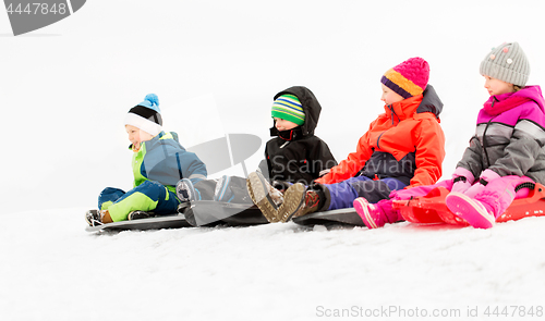 Image of happy little kids sliding on sleds in winter