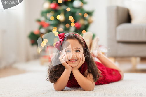 Image of happy girl lying on floor at home on christmas
