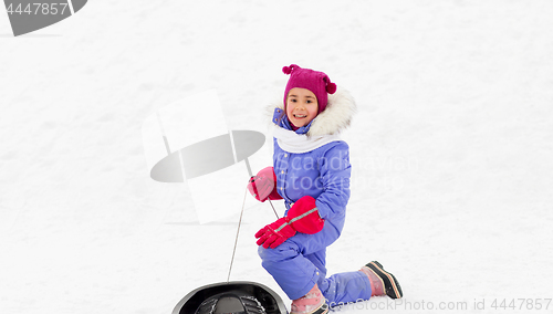 Image of happy little girl with sled on snow hill in winter