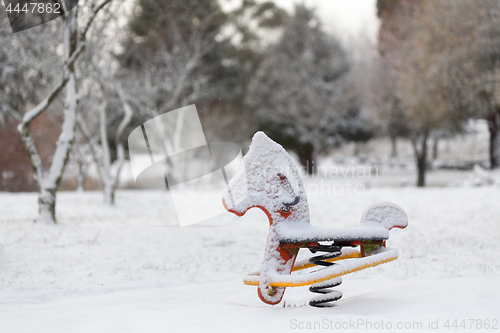 Image of Playground equipment rocking horse covered in snow