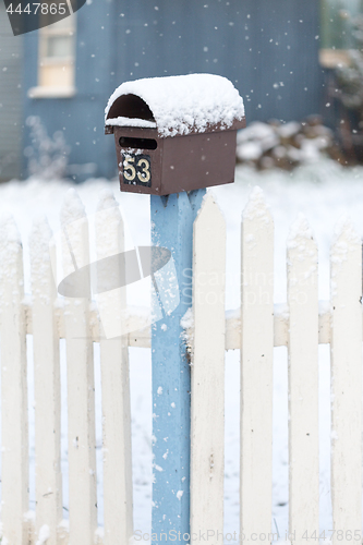 Image of Mailbox and picket fence with falling snow in winter