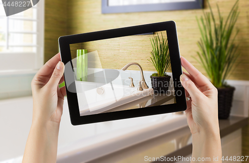 Image of Female Hands Holding Computer Tablet In Bathroom with Photo on S