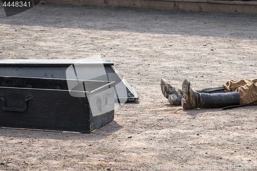 Image of Coffin next to a dead man with his boots