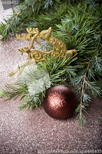 Image of Evergreen fir tree branch, golden deer, brown ball.