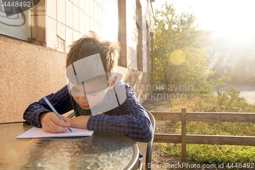 Image of Boy doing homework outdoors