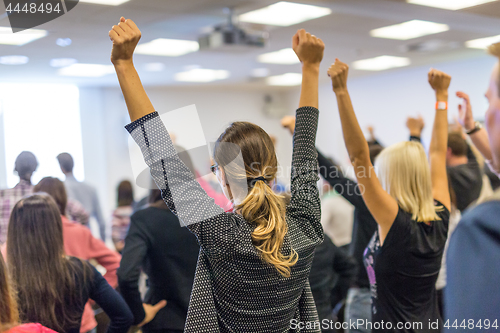 Image of Participants of interactive motivational speech feeling empowered and motivated, hands raised high in the air.